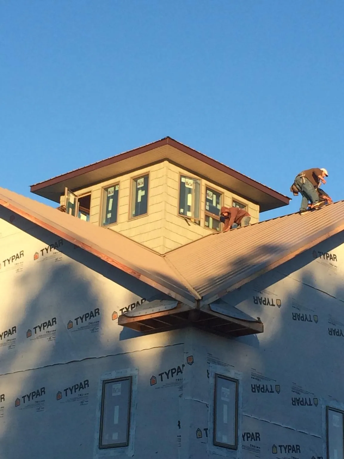 Roofers working around a rooftop cupola on a new metal roof at sunset — Roof Waterproofing in Springfield by Roofing Brothers